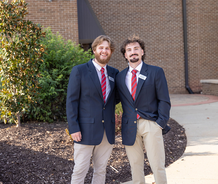 two male student ambassadors dressing nicely and working a college function