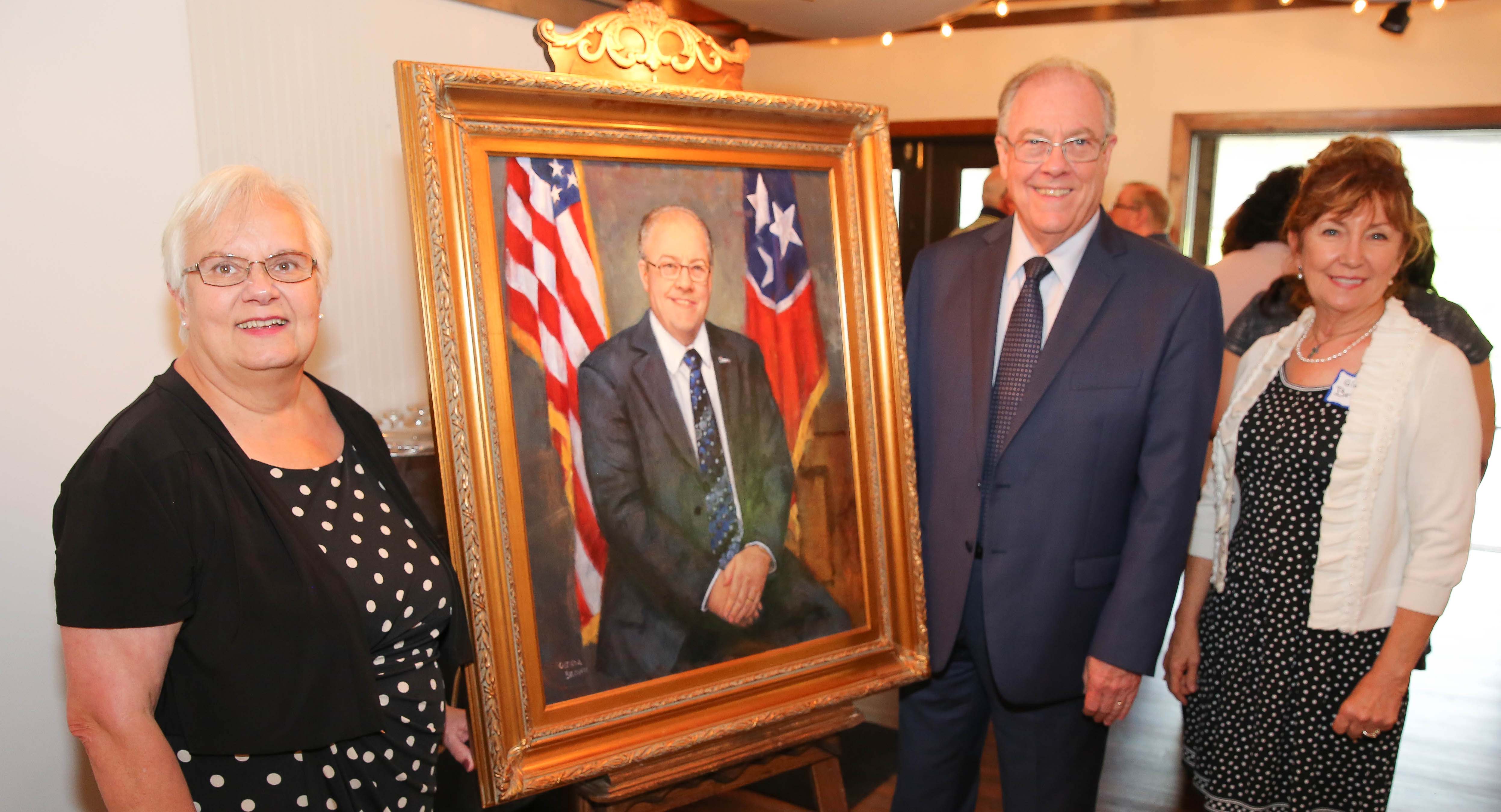 Wanda Faulkner and Jerry Faulkner pose with his portrait, painted by Glenda Shaw Brown (right).