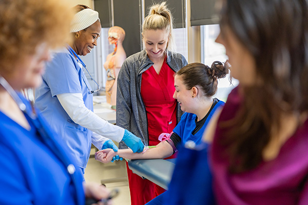 students learning to put an IV into an arm