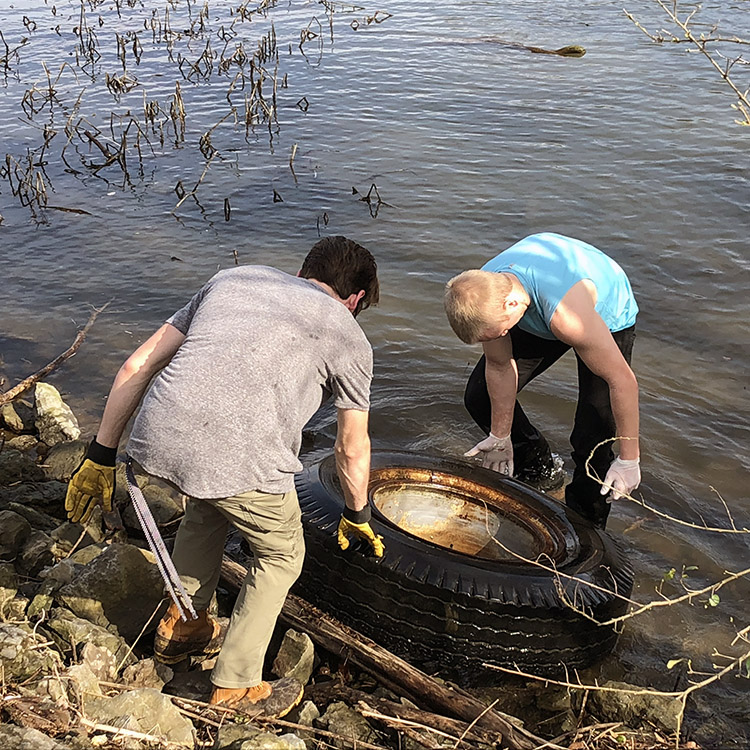 students cleaning up trash from a lake