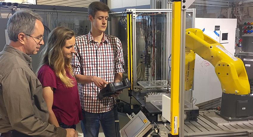 Vol State professor Tim Dean works on a robotic arm with students Tallen Gooch and Samuel Griffin in the Cookeville Mechatronics lab.