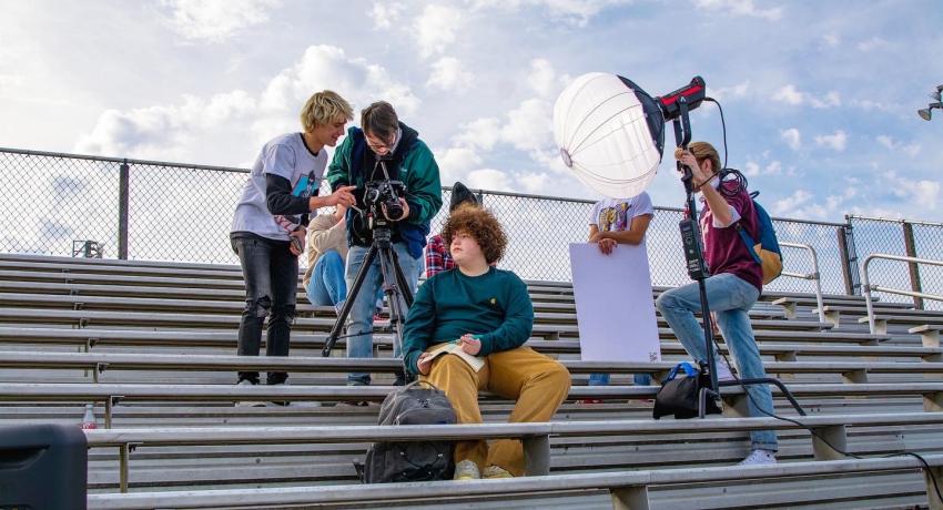production crew setting up for filming from the baseball bleachers