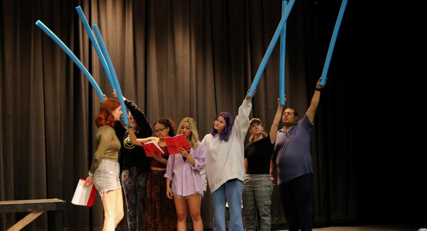 Theatre students holding pool noodles in the air