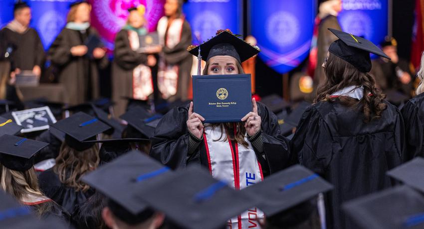 an excited graduate posing with her diploma