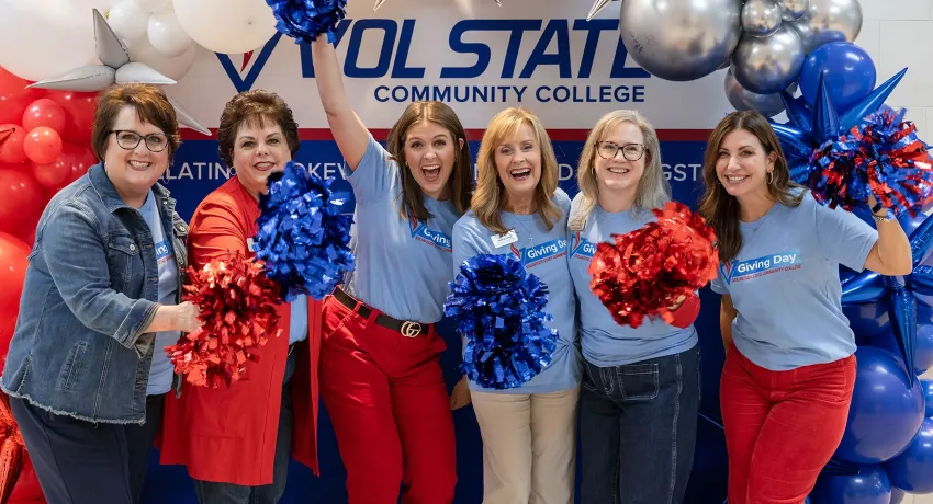 The College Foundation employees celebrating the success of Giving Day 2025 with pom-poms and balloons.