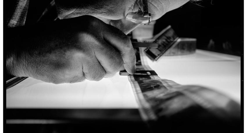 Photographer Alan Messer examining film negatives 