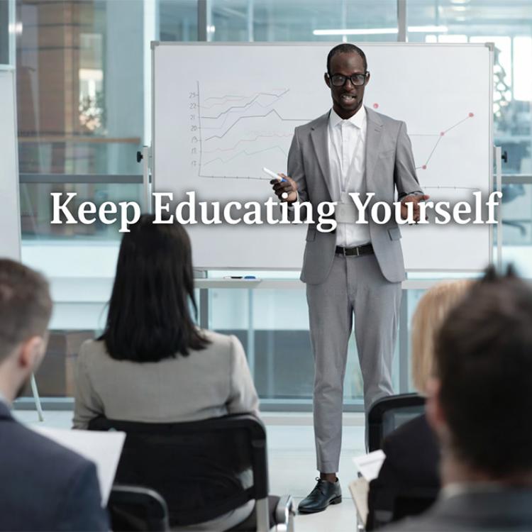 An instructor dressed in a grey suit leading a class or professionally dressed students