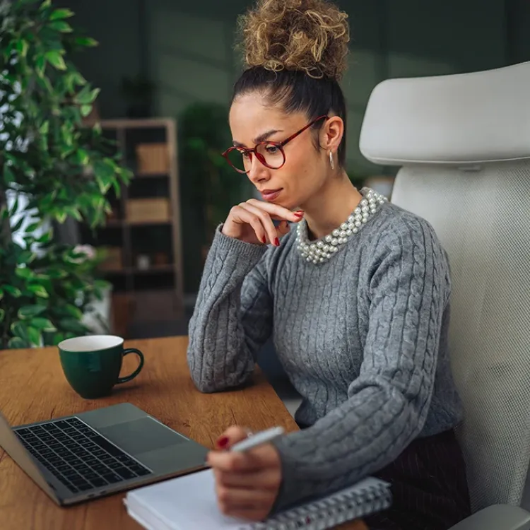 woman taking notes during an online training course on her laptop